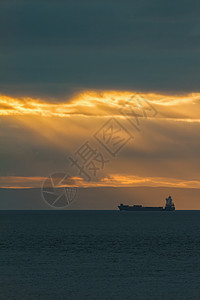 日落时海上集装箱货船双轮光图片