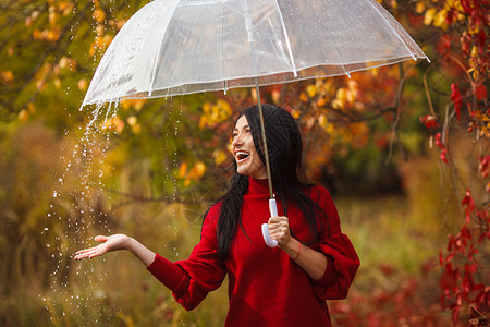 美丽的女人在雨中打着伞图片