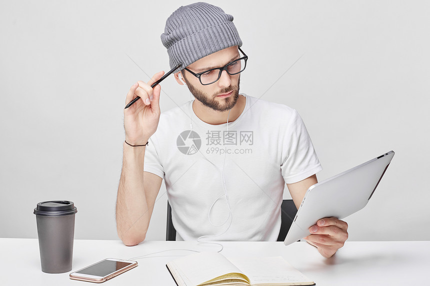 严肃的男工坐在工作场所检查电子邮件或在数字平板电脑上阅读世界新闻图片
