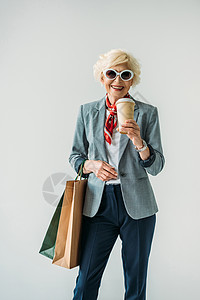 身带购物袋和咖啡的高级妇女在图片