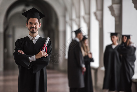 穿着学术着装的成功毕业生在大学厅里说话图片