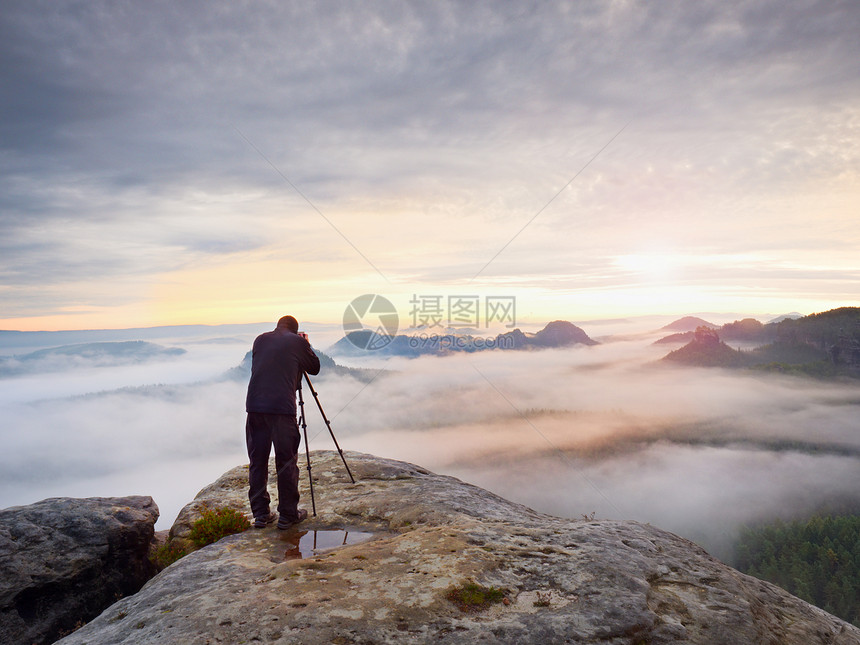 摄影师用取景器取景摄影爱好者在岩石山顶享受秋季大自然的作品梦幻般的风景图片