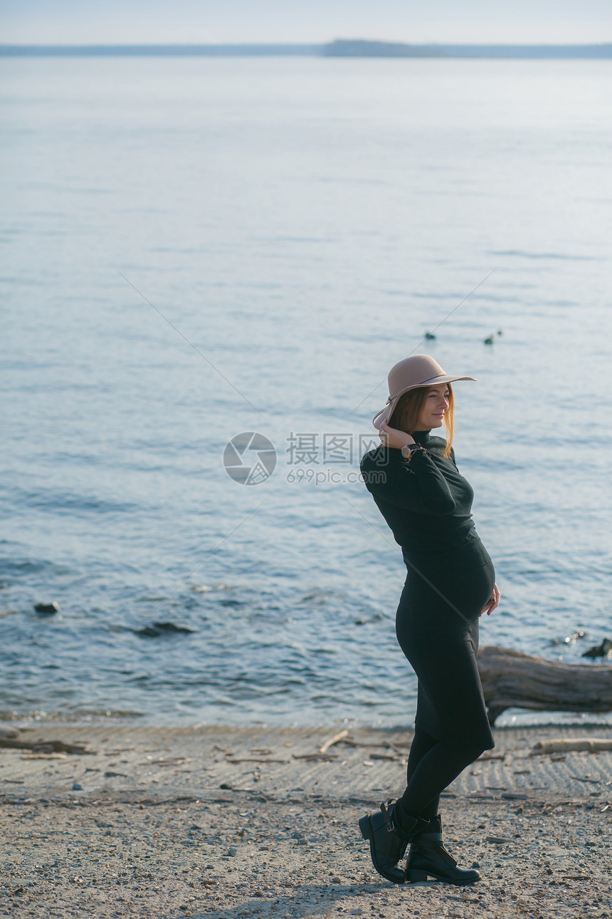 一个美丽的年轻孕妇穿着黑色高领毛衣和黑色紧身裙图片