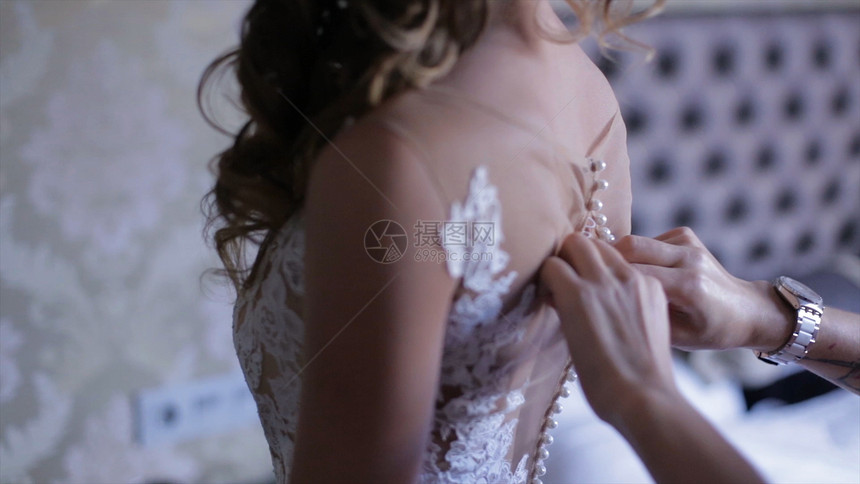 新娘伴娘帮助新娘穿裙子新娘系带礼服伴娘在婚纱上系蝴蝶图片