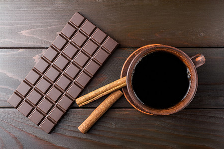棕色粘土杯中的热黑咖啡深巧克力棒和木图片