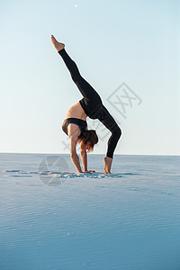 年青女在练习反向平衡瑜伽在沙滩上站立背景图片