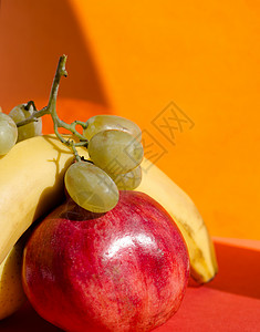 金苹果香蕉石榴和葡萄以橙色为背图片