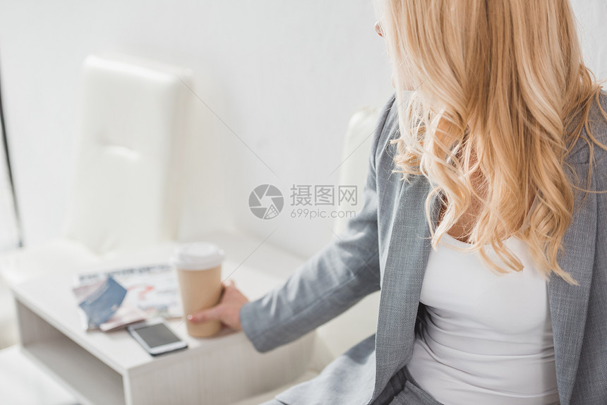 从桌子上拿纸杯咖啡的女商人拍图片