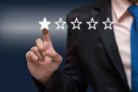 商人指着五星符号来提高公司或酒店在暗色调背景下的评级商业评价概图片