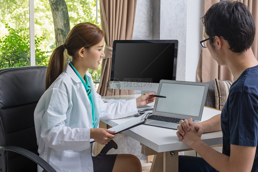亚洲年轻医生在现代医院办公室使用技术笔记本电脑与患者讨论健康诊图片