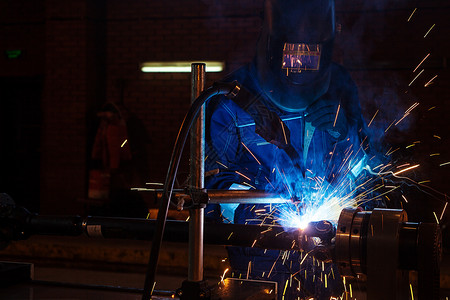 用于万向轴修复的自动焊接机上焊接面罩烹饪金属的蓝色制服特写男图片