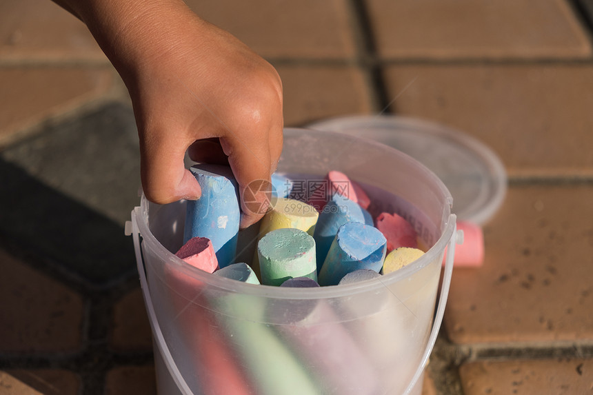儿童从户外的塑料桶中采摘大型彩色粉笔图片