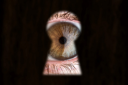 妇女棕色眼睛透过钥匙孔看图片