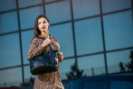 街上身穿着衣服的年轻美女拿着一个旅行图片