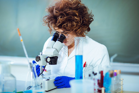 实验室的女科学家年轻的科学家在实验室里通过显微镜观察做一些研究图片