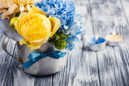 锡杯中的黄色玫瑰和蓝色绣球花束图片