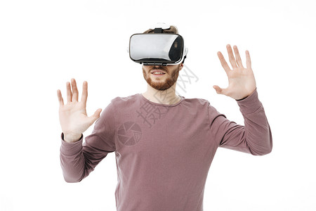 在白色背景上使用虚拟现实眼镜的年轻微笑男人的肖像酷帅男孩乐于与视觉现实相背景图片