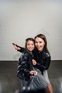 时尚的女儿和母亲用自拍杆自拍图片