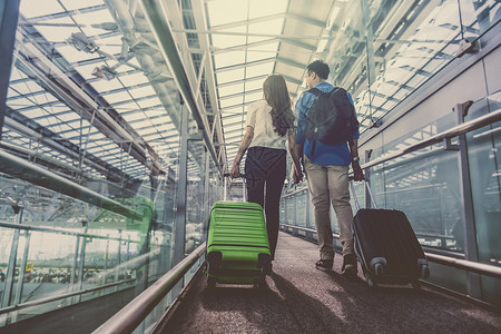 带着手提箱的亚洲夫妇旅客在机场具有技术概念的恋图片