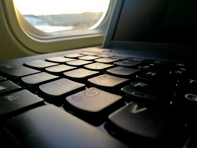 飞机舱窗户座位附近的膝上型电脑键背景图片