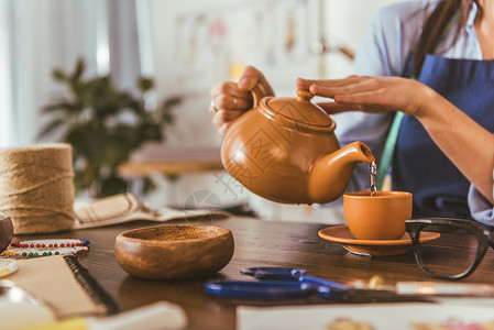 裁缝在午餐时在杯子里倒茶的裁剪图像图片