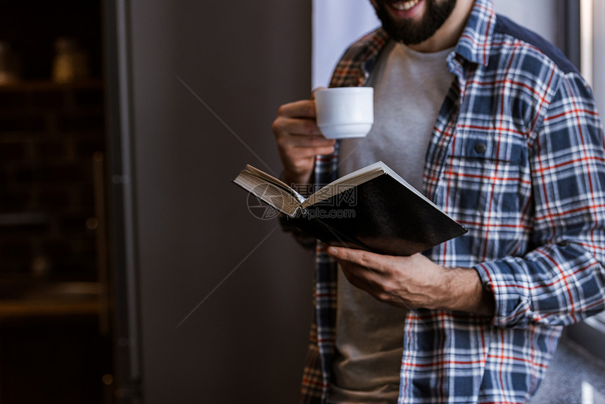 以咖啡杯站在窗边和阅读书旁的喜人风图片