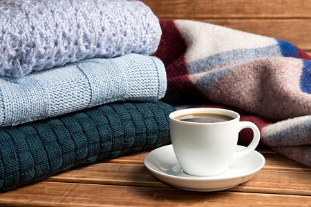 堆满了温暖的毛衣和毯子穿回式滑雪鞋和一杯咖啡温暖和舒适的概念图片