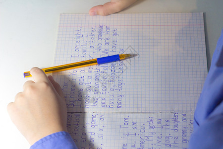 男孩手的特写镜头用铅笔在传统的白色记事本纸上手写英文单词男图片