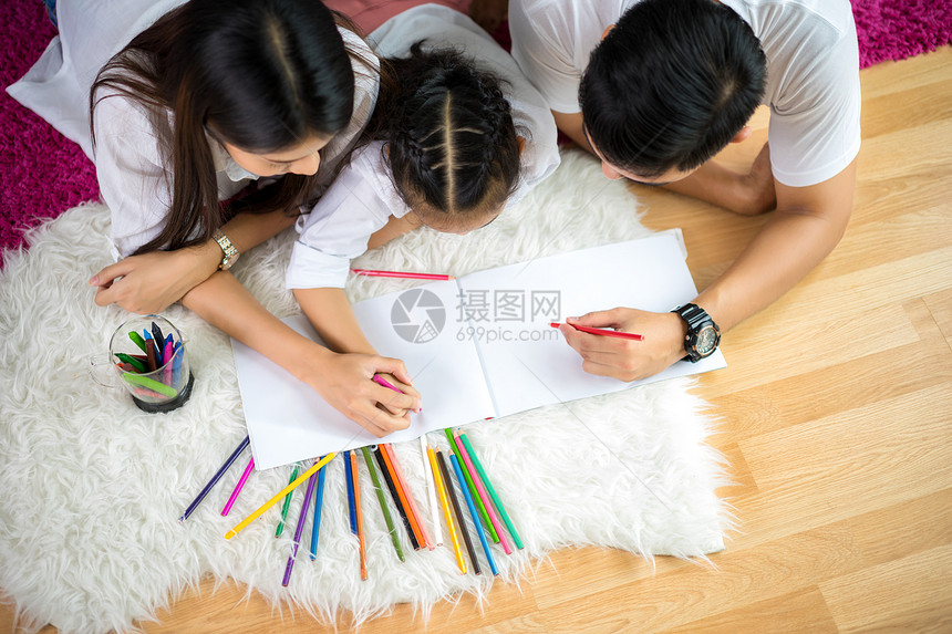 年轻家庭与多彩的铅笔一起在家里画图片