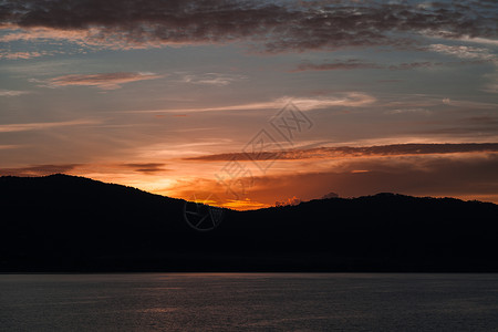 美丽的夕阳在山丘和水面的轮廓上图片