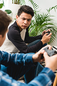愤怒的少年男孩在玩电子游戏时互相看对方图片