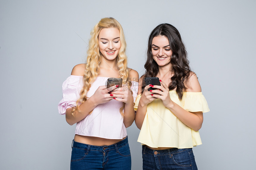 两个年轻最好的朋友女在社交网里忙着使用手机图片