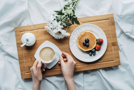 妇女用煎饼和咖啡在床上吃早图片