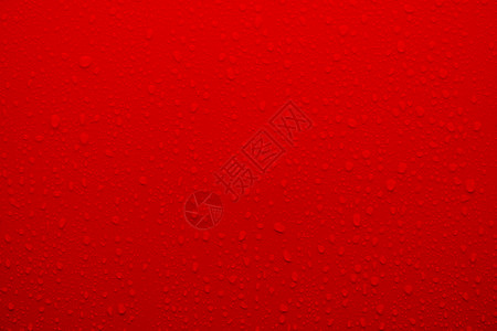 作为背景的红色表面上的冷凝水滴图片