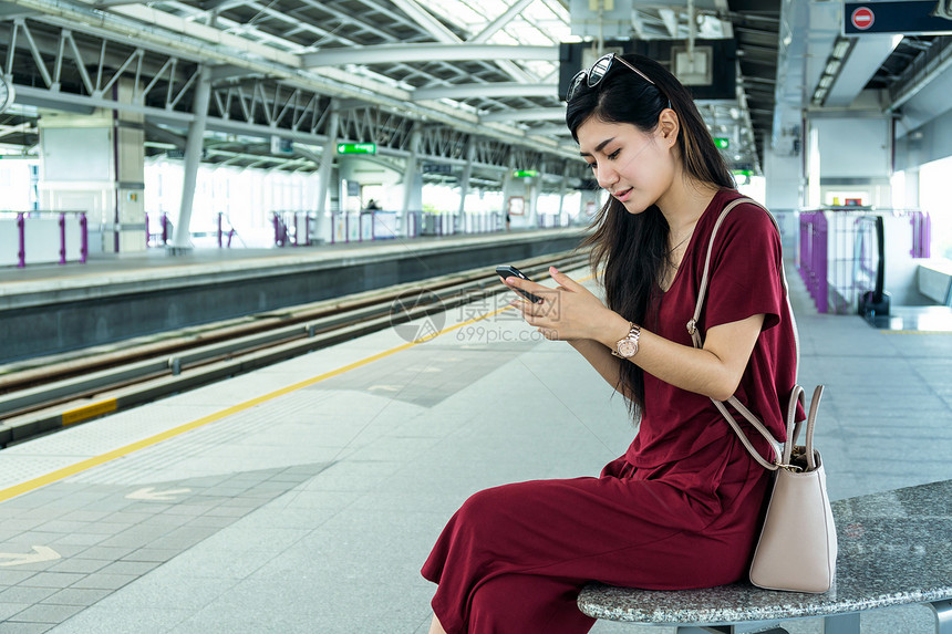 利用BTSSkytrain铁路或MRT地铁的智能移动电话使用社交网络在大城市旅行生活方式和交通概念中搭乘临时穿便衣图片
