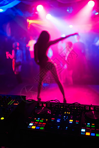 夜总会现场一名苗条女孩在彩色背景和音乐设备上跳舞的明亮背景和图片