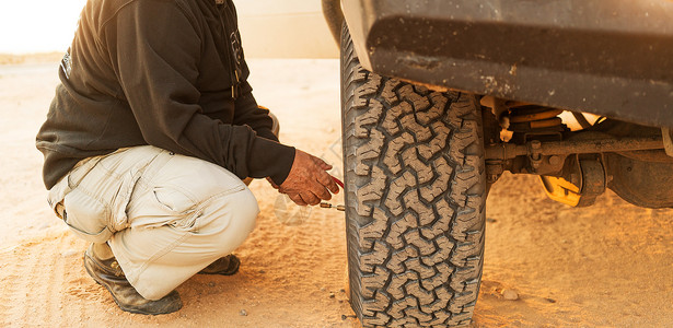 男人用计时器测量轮胎压力图片