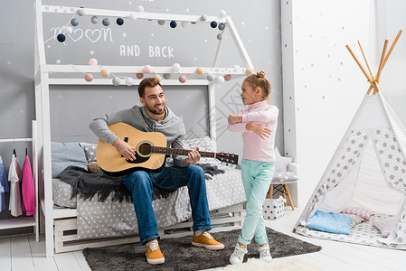 年轻父亲在女儿卧室里弹吉他当她着女儿图片