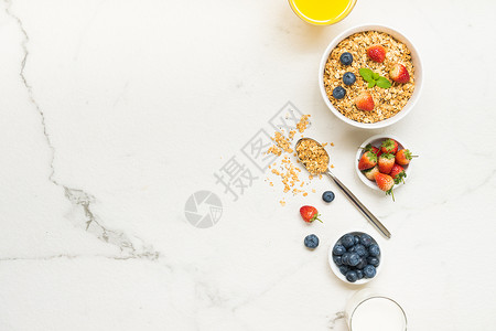 以蓝莓草莓和黑咖啡牛奶及橙汁为白石桌背景的Granola图片
