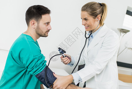 在诊所检查病人血压的女图片