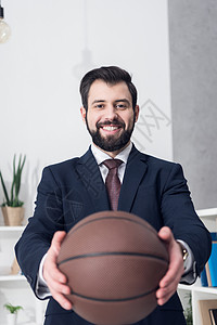 有选择地关注微笑的商人展示篮球在办公室图片