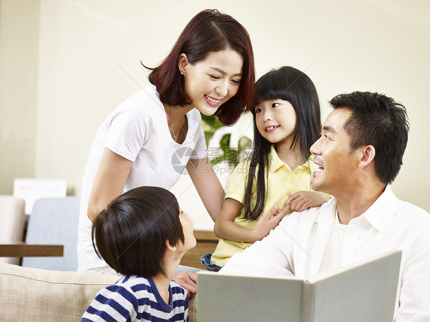 亚洲父母亲和父亲和两个孩子儿和女儿一起读一本图片