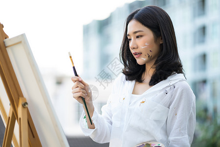 女艺术家画在里的画布上看画笔图片