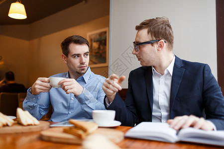 两个商业人士在咖啡馆午餐临时会议期间聊天时讲图片