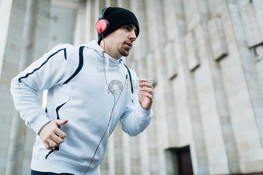 体育运动员在体育场上奔跑用耳机收听图片