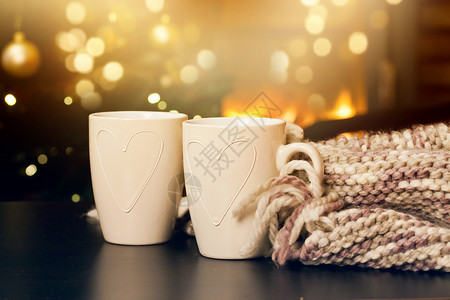 2个茶杯编织围巾圣诞树和壁炉图片