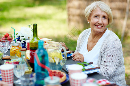 祖母坐在野餐桌边看图片