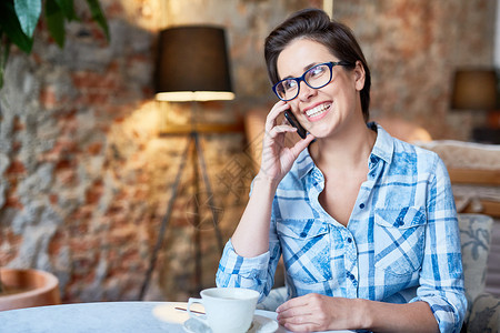 穿着眼镜的开心女人在咖啡馆喝茶时图片