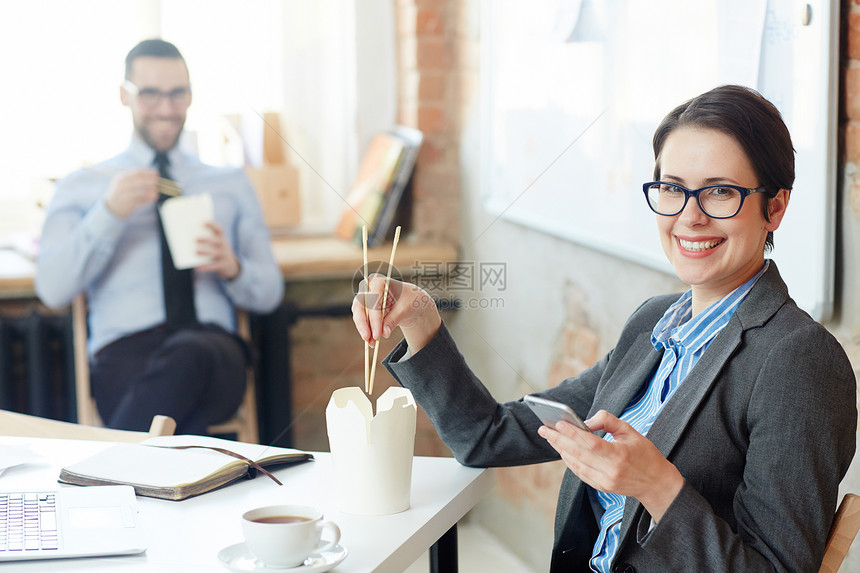 快乐的女商人拿着筷子吃外图片