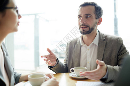 自信的商人解释他的想法给咖啡断裂的图片